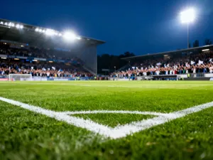 Piłkarz w stroju reprezentacji Ekwadoru prowadzi piłkę na murawie stadionu w świetle zachodzącego słońca.